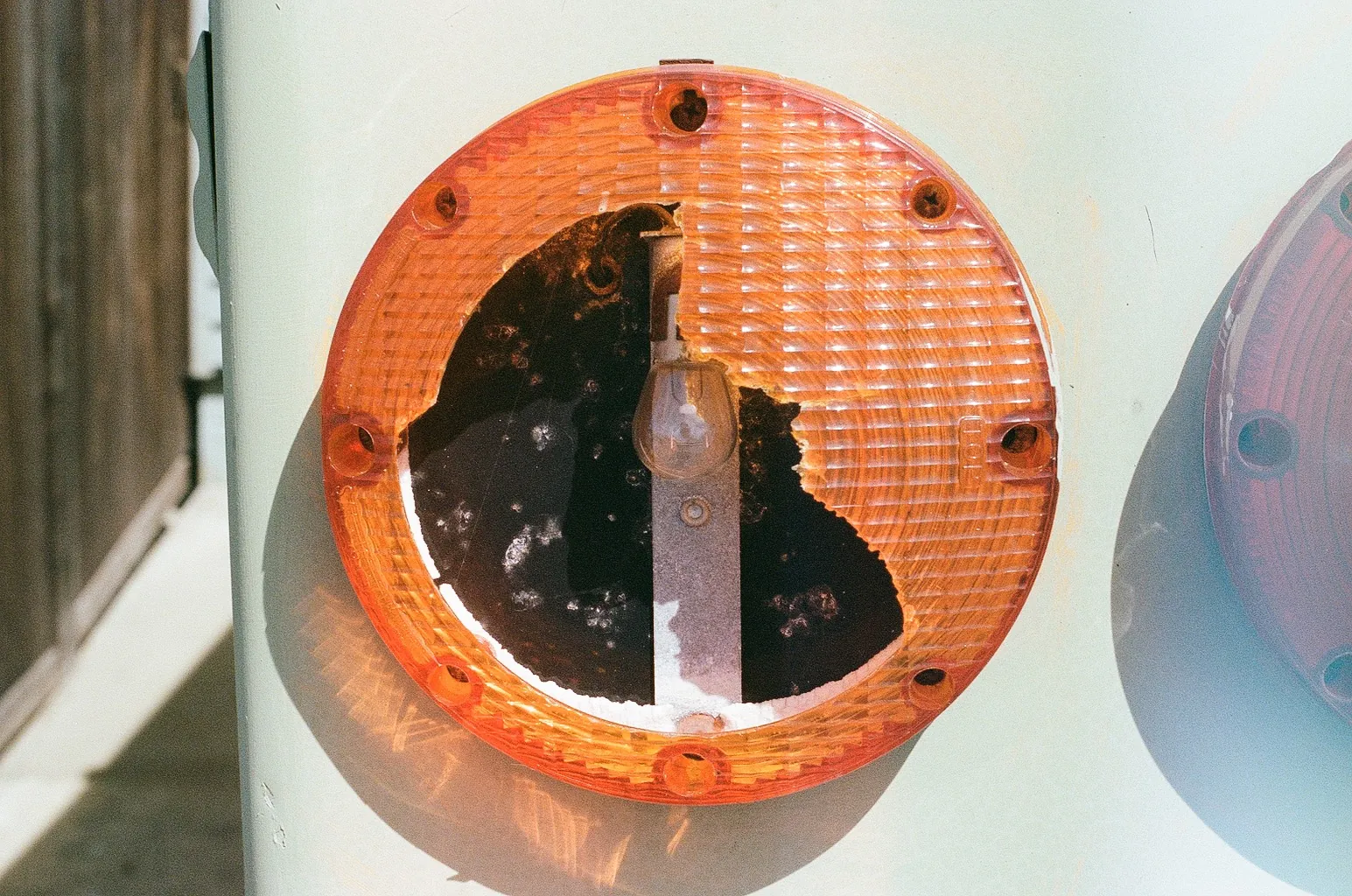 A cracked orange light lens on a white wall