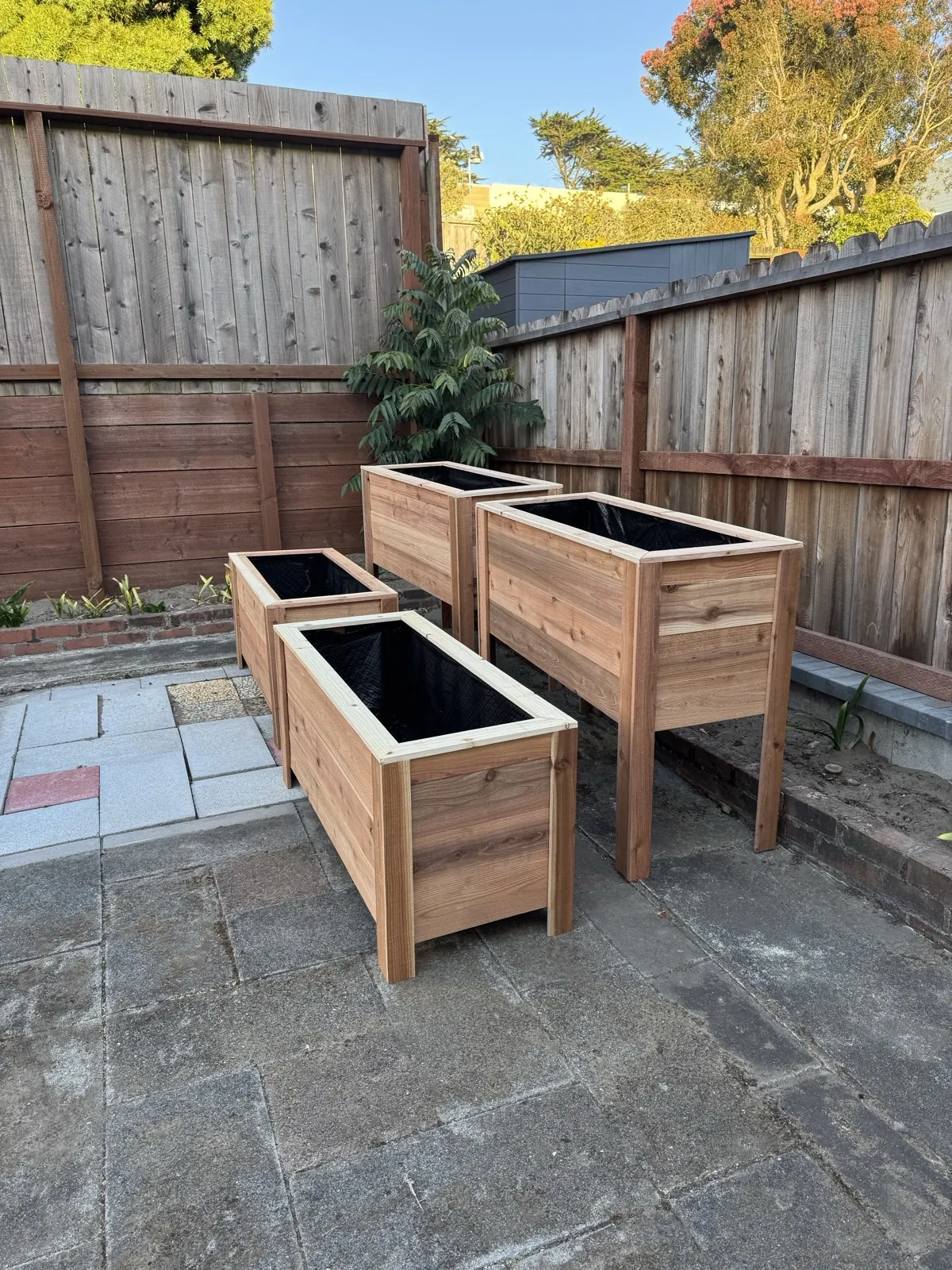 Three finished cedar planter boxes in a backyard